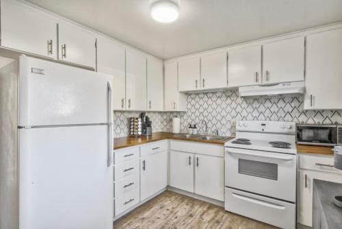 a kitchen with white cabinets and a white refrigerator at Kings Hideaway Stylish Apartment with Scenic View in Colorado Springs