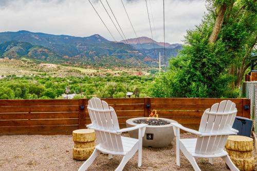 two white chairs and a table on a patio with mountains at Kings Hideaway Stylish Apartment with Scenic View in Colorado Springs