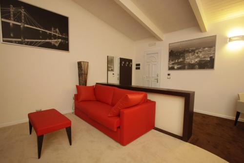 a living room with a red couch and a red stool at Hotel Paradise Airport in Forlì