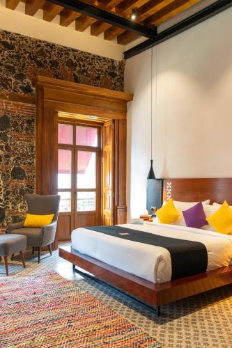 a bedroom with a large bed and a chair at Casa de la Luz Hotel Boutique in Mexico City