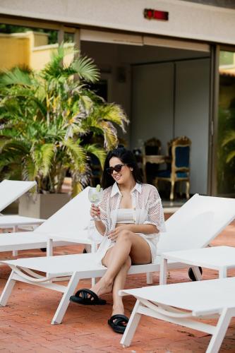 a woman sitting on a chair with a glass of wine at Porto Bello Hotel Boutique in Puerto Colombia