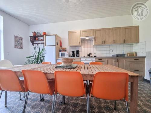 - une cuisine avec une table en bois et des chaises orange dans l'établissement Villa spacieuse avec jardin, terrasse, et équipements complets à Baives, proche Belgique et Val Joly - FR-1-510-218, à Baives