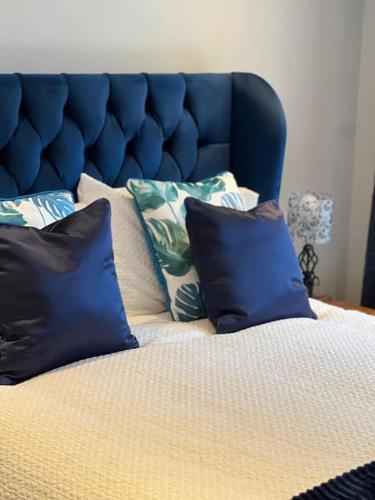 a bed with a blue headboard with pillows on it at Brackley Guest house in Brackley