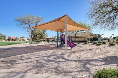 a playground with a tan umbrella and purple swings at Kiva Cove Pool & Sun Loungers on the Patio in Mesa