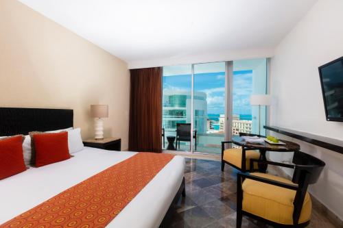 a hotel room with a bed and a desk with a view at Krystal Grand Cancun All Inclusive in Cancún