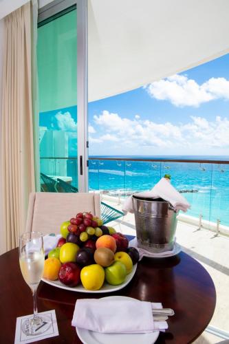 a plate of fruit on a table with a view of the ocean at Krystal Grand Cancun All Inclusive in Cancún
