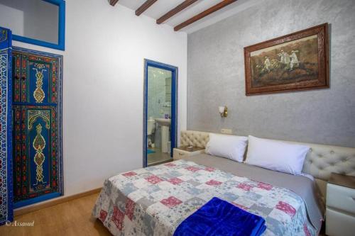 a bedroom with a bed and a painting on the wall at casa yasminna in Chefchaouene