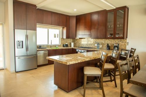 a kitchen with wooden cabinets and a island with chairs at 113 Big Town House For Family W Pool in Cabo San Lucas