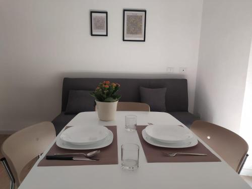 une table avec des assiettes et un vase de fleurs dans l'établissement LorMar House, à Oristano