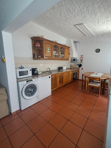a kitchen with a washing machine and a table at Sweet Living Alentejo in Brinches