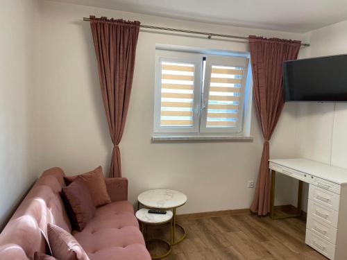 a living room with a couch and a desk and a window at Apartamenty Zator Energy Rest in Zator