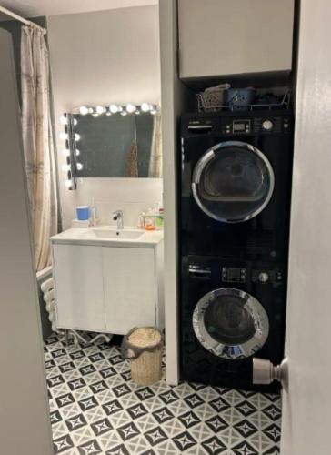 une salle de bain avec une machine à laver et un lavabo dans l'établissement Appartement familial 3ch balcon Tour Eiffel 15min, à Paris