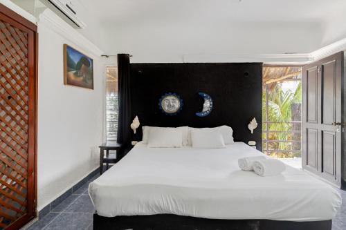 - une chambre avec un grand lit blanc et une tête de lit noire dans l'établissement Mayan Art Hotel a unos pasos de la 5a Avenida, à Playa del Carmen