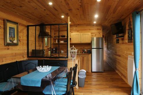 a dining room with a table and a refrigerator at La Roulotte d'Ala-Daims in Nollevaux