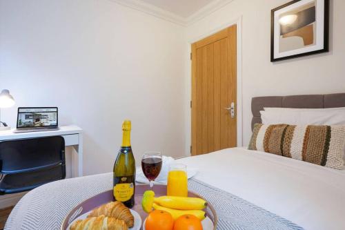 a table with a plate of fruit and a bottle of wine at Stylish Apartment - Central Location - Free Parking, Self-Check-In, Fast Wifi and Smart TV by Yoko Property in Northampton