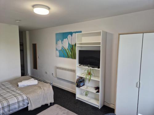 a bedroom with a bed and a cabinet with a television at Legends Court, Wolverhampton in Wolverhampton