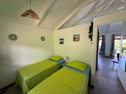 two beds in a room with green sheets at Moemiti in Moorea