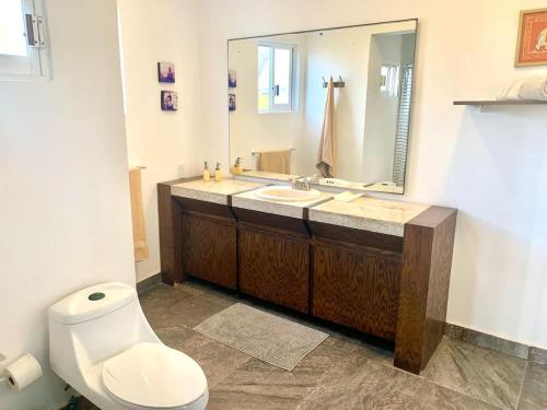 a bathroom with a toilet and a sink and a mirror at Casa de las Olas Surf & Beach Club in Acapulco