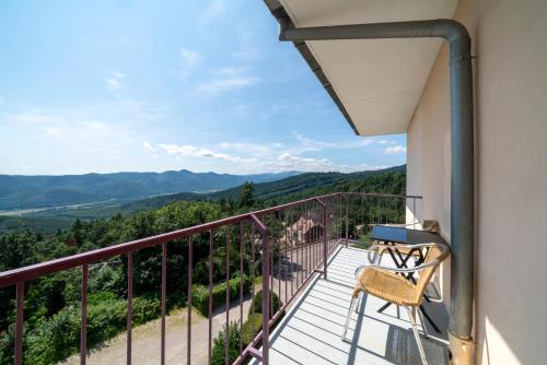 a balcony with a chair and a view of the mountains at Alexain Hotel Restaurant & Wellness - Colmar Ouest in Trois-Épis