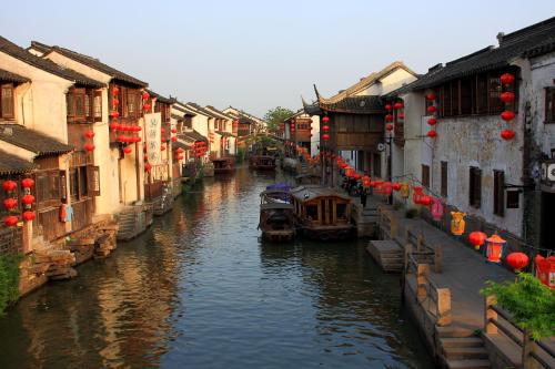 a canal with boats in a city with buildings at Hotel Indigo Suzhou Jinji Lake by IHG in Suzhou