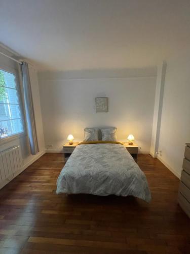 - une chambre avec un lit et deux lampes sur deux tables dans l'établissement Appartement aux portes de Paris, à Alfortville