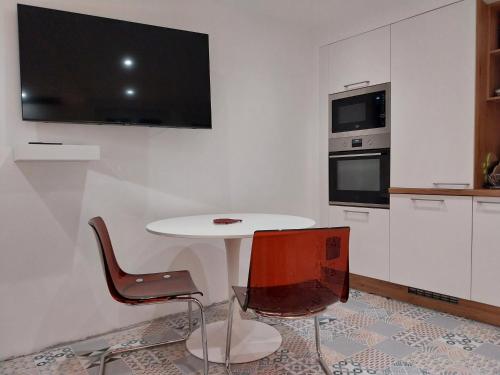 - une cuisine blanche avec une table et deux chaises dans l'établissement Entre Mer & Terre, à Banyuls-sur-Mer