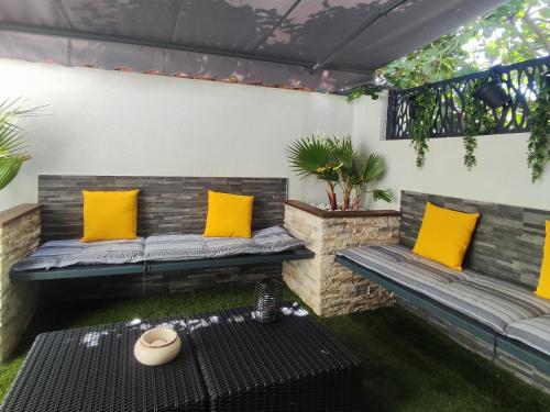 a patio with two benches with yellow pillows and a table at R luxury piscine et spa privatifs in Colmar