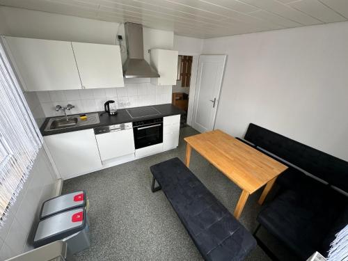 a small kitchen with a wooden table and a black couch at Comfort Apartments Heilbronn in Heilbronn