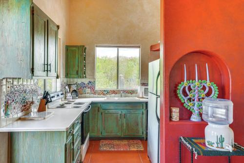 a kitchen with green cabinets and a red wall at Chic Tucson Casita with Deck and Panoramic Views! in Tucson