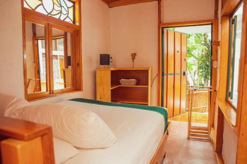 a bedroom with a bed and a door to a balcony at El Dragon Hotel in San Marcos La Laguna