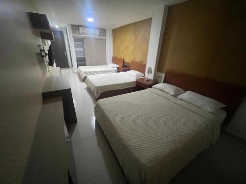a hotel room with two beds and a television at Hotel Prado 72 INN in Barranquilla
