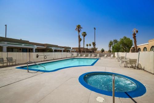 a swimming pool with chairs and a fence at Sure Stay Plus by Best Western Twentynine Palms Joshua Tree in Twentynine Palms
