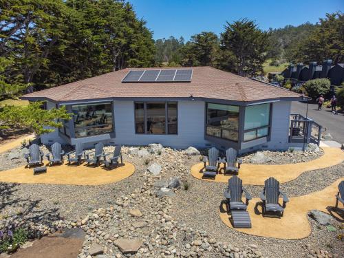 a house with solar panels on the roof and chairs at Windrush Inn - Cambria in Cambria