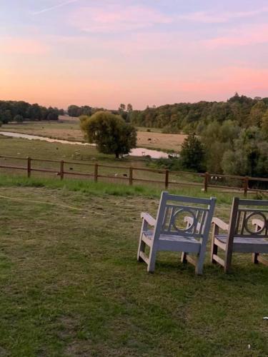 two blue benches sitting in a field near a fence at NEW RENOVATED FARM river view Cabin with wood burner pet friendly fire pit bbq in Bramfield