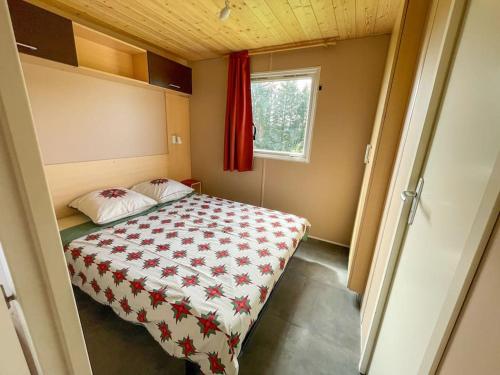 - une petite chambre avec un lit et un rideau rouge dans l'établissement Bungalow - La Petite Sibérie - Nature - Familial, à Mazet-Saint-Voy