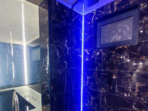 a bathroom with a tv on a blue tiled wall at R luxury piscine et spa privatifs in Colmar