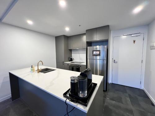 a kitchen with a white counter and a refrigerator at Midnight Luxe 2BR 2Bath 2Car 528 in the heart of Braddon Pool Sauna Gym Secure Parking Wifi Wine in Canberra