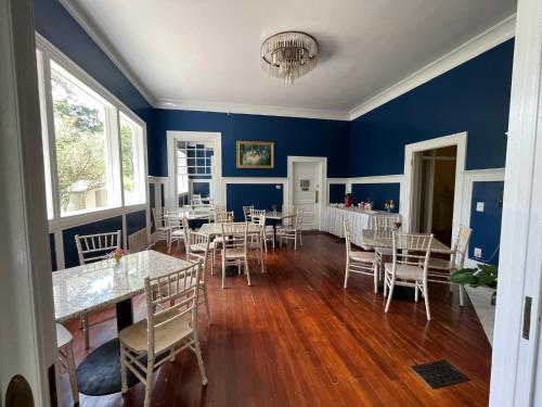 a dining room with blue walls and tables and chairs at Historic Michabelle Inn in Hammond