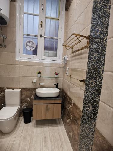 a bathroom with a toilet and a sink and a window at family suites cairo downtown in Cairo