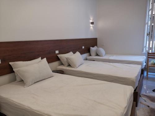 two beds in a room with white sheets and pillows at family suites cairo downtown in Cairo