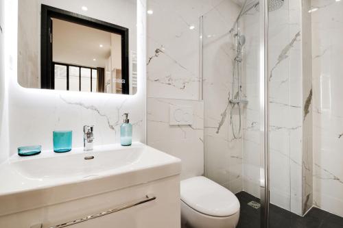 une salle de bain blanche avec un lavabo et une douche dans l'établissement Elegant Appartement neuf 2 BDR 6P - Republique, à Paris