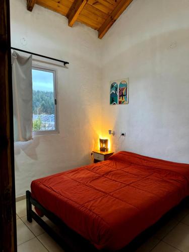 a bedroom with a red bed and a window at Hostel Otto Tipp in El Bolsón