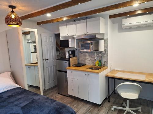 ロンゲールにあるWell Equipped Studio FOR NON-SMOKING GUESTS ONLY CITQ ЗO9467の白いキャビネットとベッドと机のある小さなキッチン
