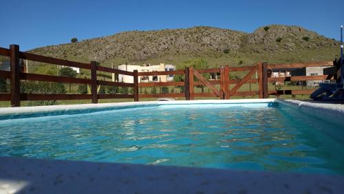 Una piscina con valla y una montaña. en Casa Ruca Maná, en Sierra de la Ventana
