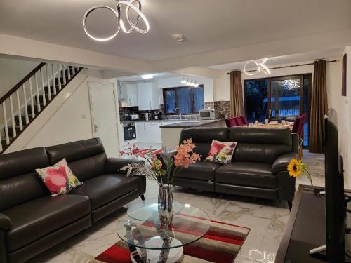 a living room with two leather couches and a glass table at 2026 Winner of Travelers Award - Four Bedroom Houses & Studio Apartments - HS2 Contractors - NEC - Birmingham Airport - BCU & Aston University - Heartland Hospital - Jaguar - Star City in Birmingham