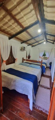 two beds in a room with wooden floors at Pouso da Cajaíba - Chalé Pedaço de Céu in Paraty