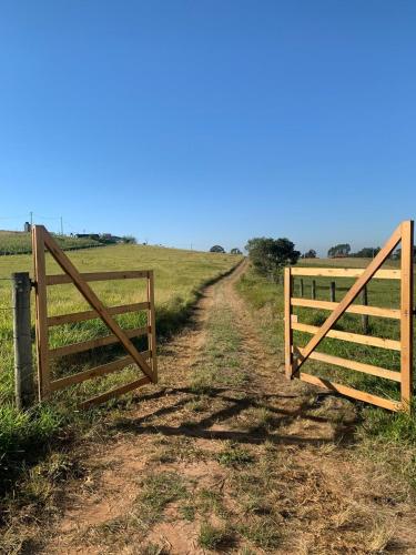 a fence on a dirt road next to a field at A Casa Cuesta Pousada in Pardinho