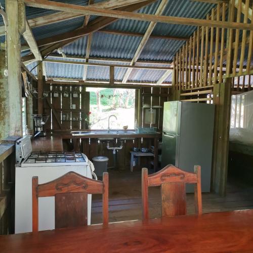 a kitchen with a stove and a refrigerator and two chairs at Pavones Rustic Jungle Cabin in Pavones