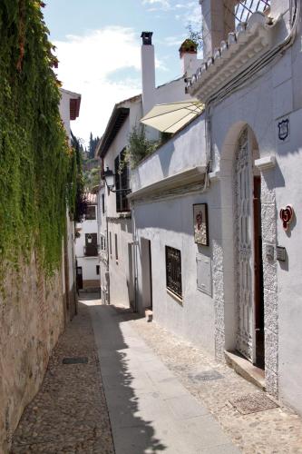 a narrow alley with white buildings and a street at Suite Comares in Granada
