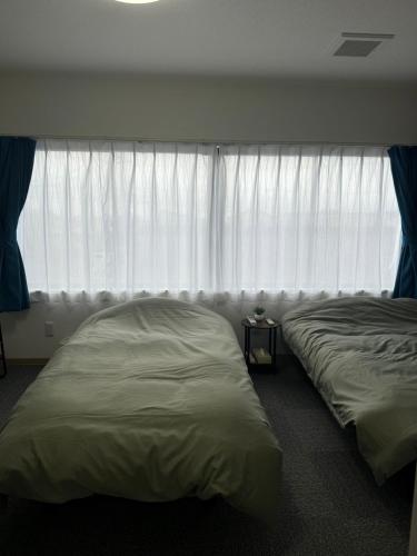 two beds sitting in a room with a window at 五所川原市街好立地 GreatLocation in Goshogawara